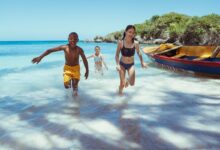 Děti běží z moře na pláž v Ocho Rios. Jamajka.